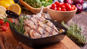 Delicious grilled meat seasoned with rosemary served with fresh vegetables on a wooden board.